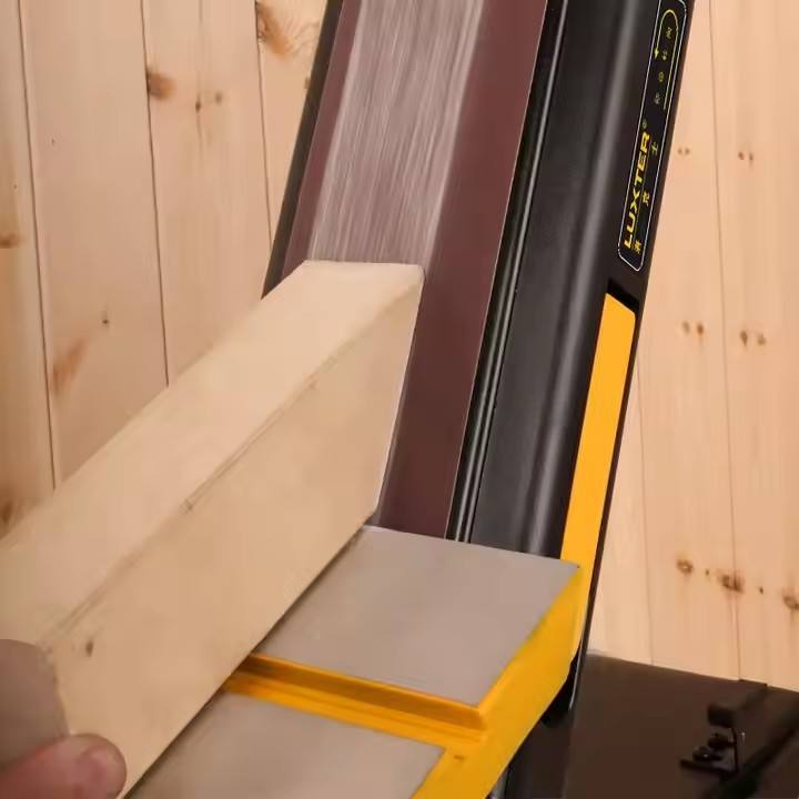 Bench belt sander sanding light wood boards with the table feed