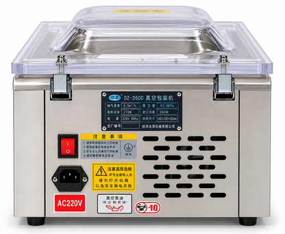 A stainless steel vacuum sealer machine with a clear plastic lid, featuring a red power switch, a black AC220V socket, and various warning labels on the front panel.
